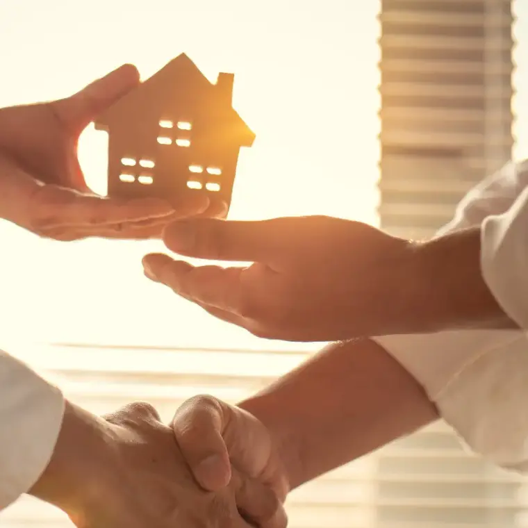 Übergabe eines Holzhauses als Symbol für einen erfolgreichen Immobilienverkauf mit Handschlag