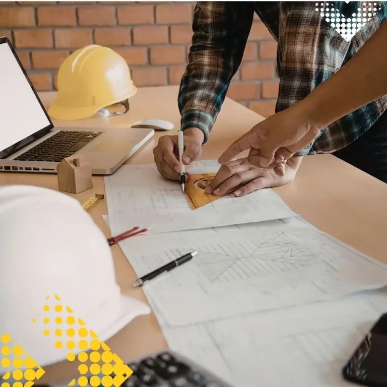 Bauunternehmer plant ein Projekt mit Bauplänen und Laptop im Büro